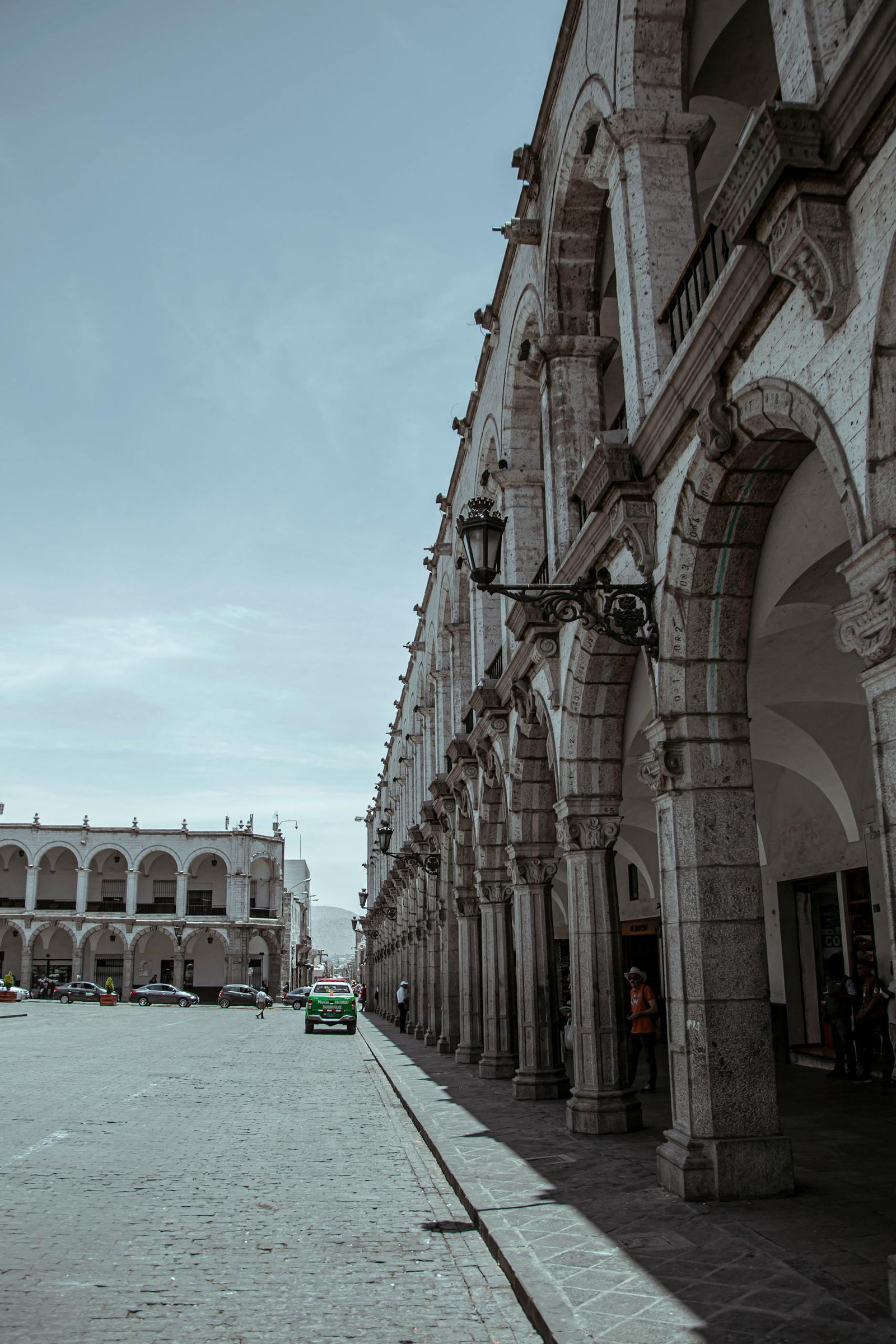 Historic colonial arches line the main plaza of Arequipa, Peru under a clear blue sky.